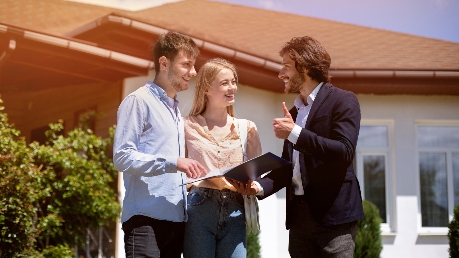 Real estate agent with happy clients outside a home, showcasing the role of transaction coordinators in delivering smooth and successful property transactions.
