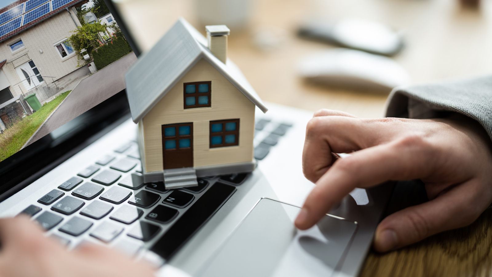 Close-up of a miniature house on a laptop keyboard, symbolizing digital tools and streamlined workflows in real estate transactions.